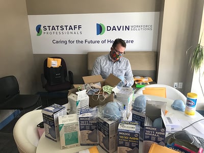 A person at a table, packing PPE into shipping bags.